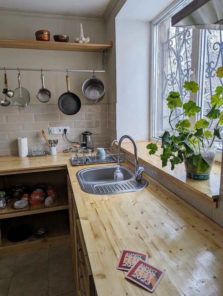 Pater25 kitchen — wooden worktop, hanging pans, window plants